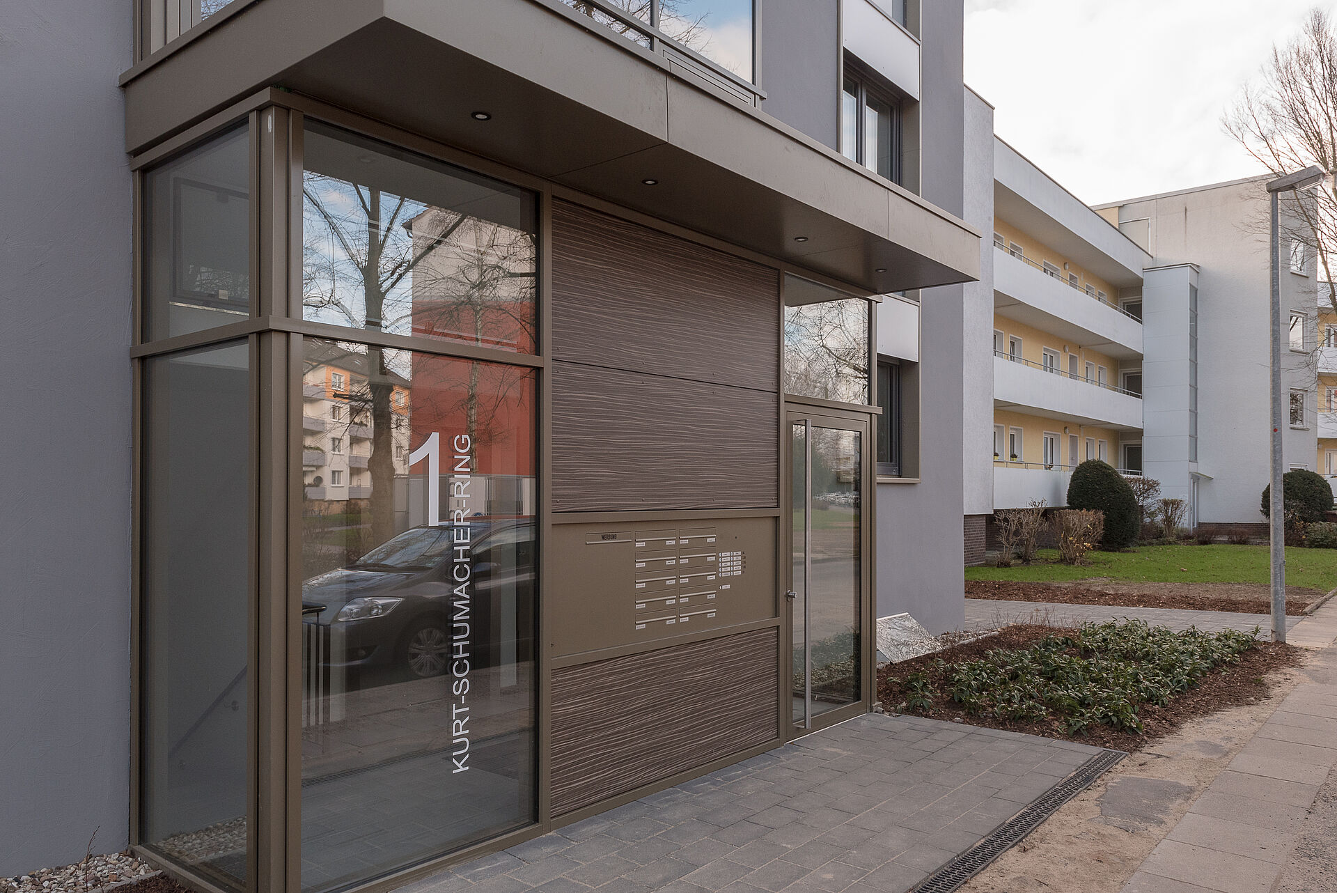 Gepflegter Hauseingang mit großen Glasfronten, Briefkästen und Klingelschildern