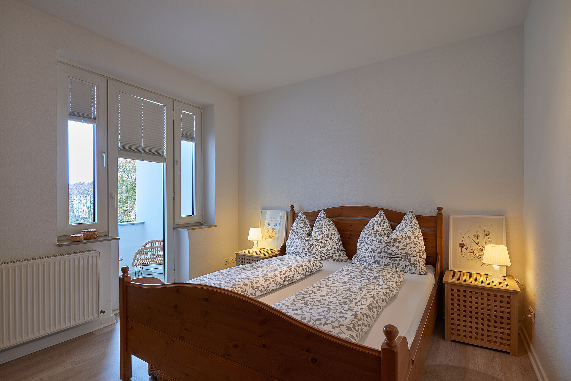 Schlafzimmer mit einem Doppelbett aus Holz, eine Tür führt auf den Balkon