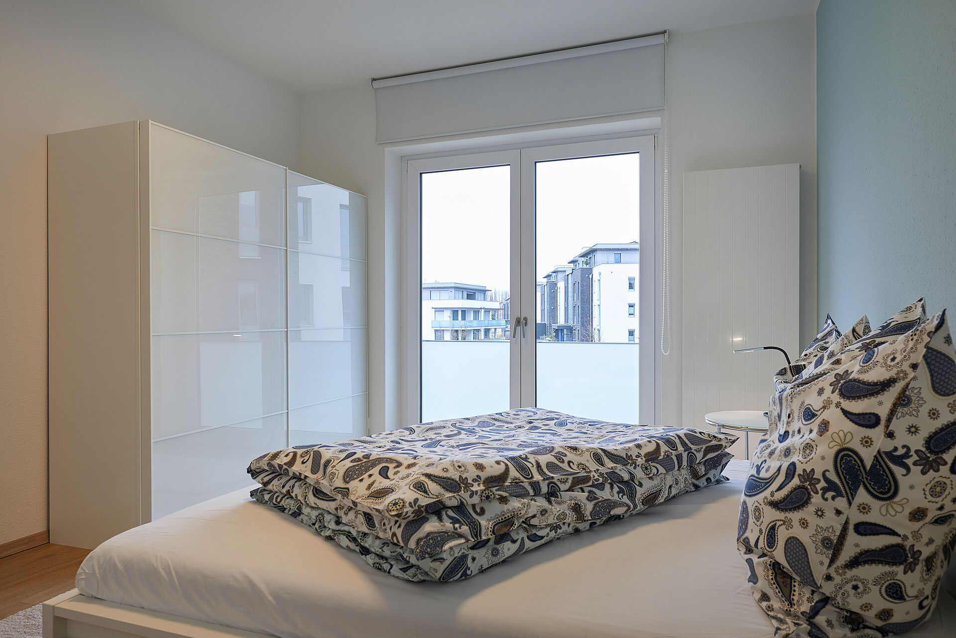 Schlafzimmer mit Balkontür, Doppelbett und einem großen weißen Kleiderschrank