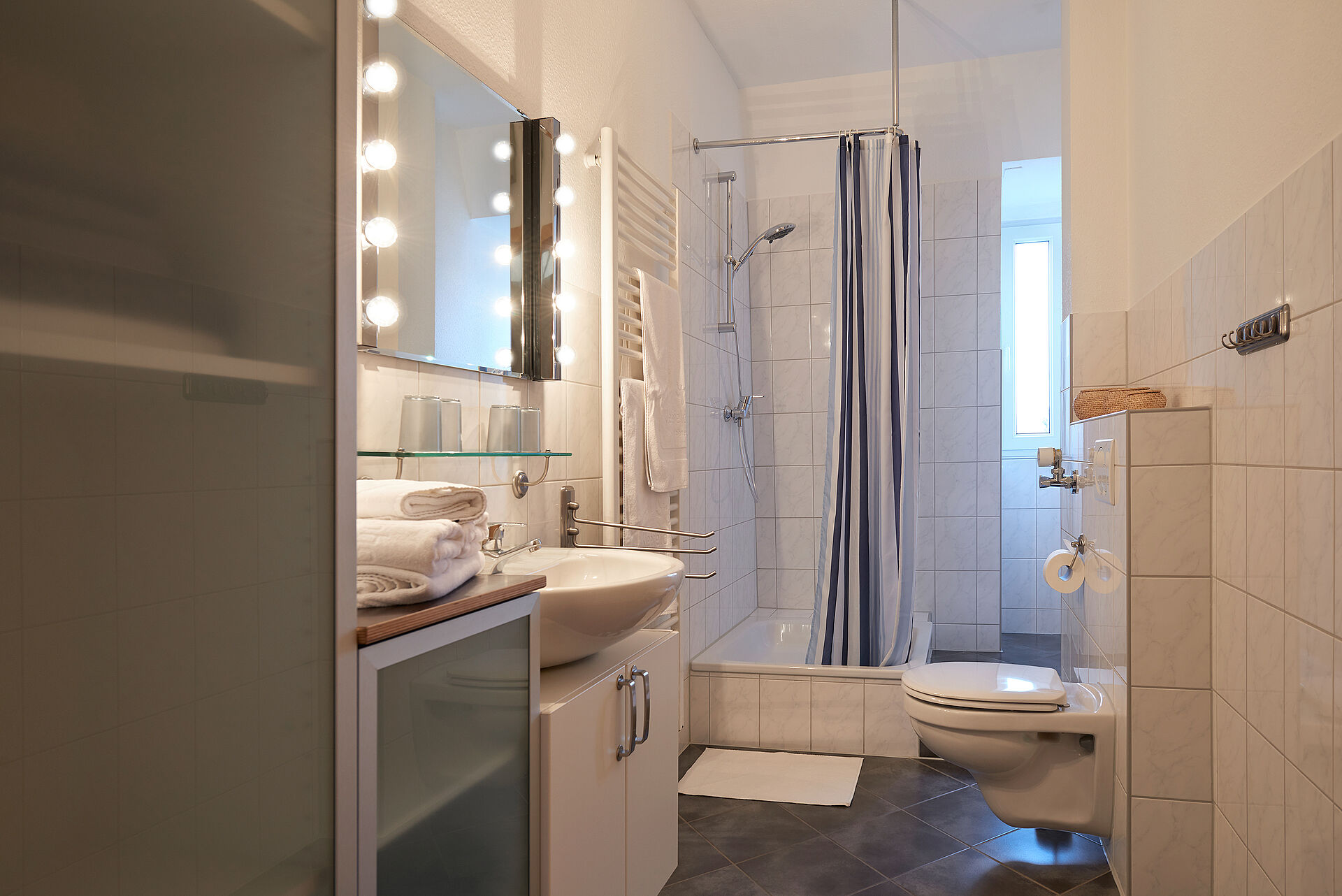 Badezimmer mit Dusche und einem beleuchteten Spiegel