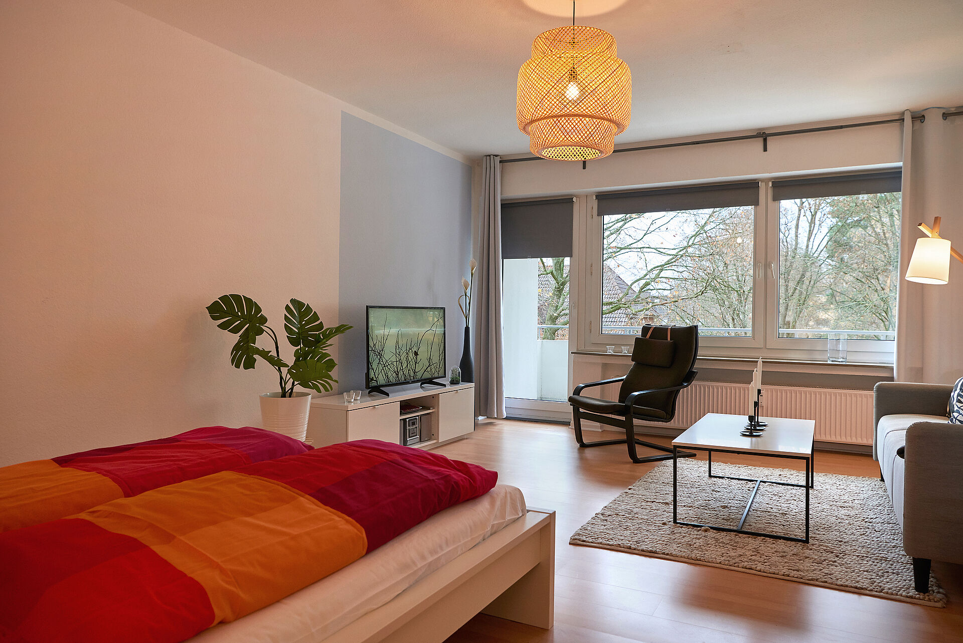 Ein helles Apartment, der Blick fällt über die Möbel Richtung Fensterfront mit Balkontür
