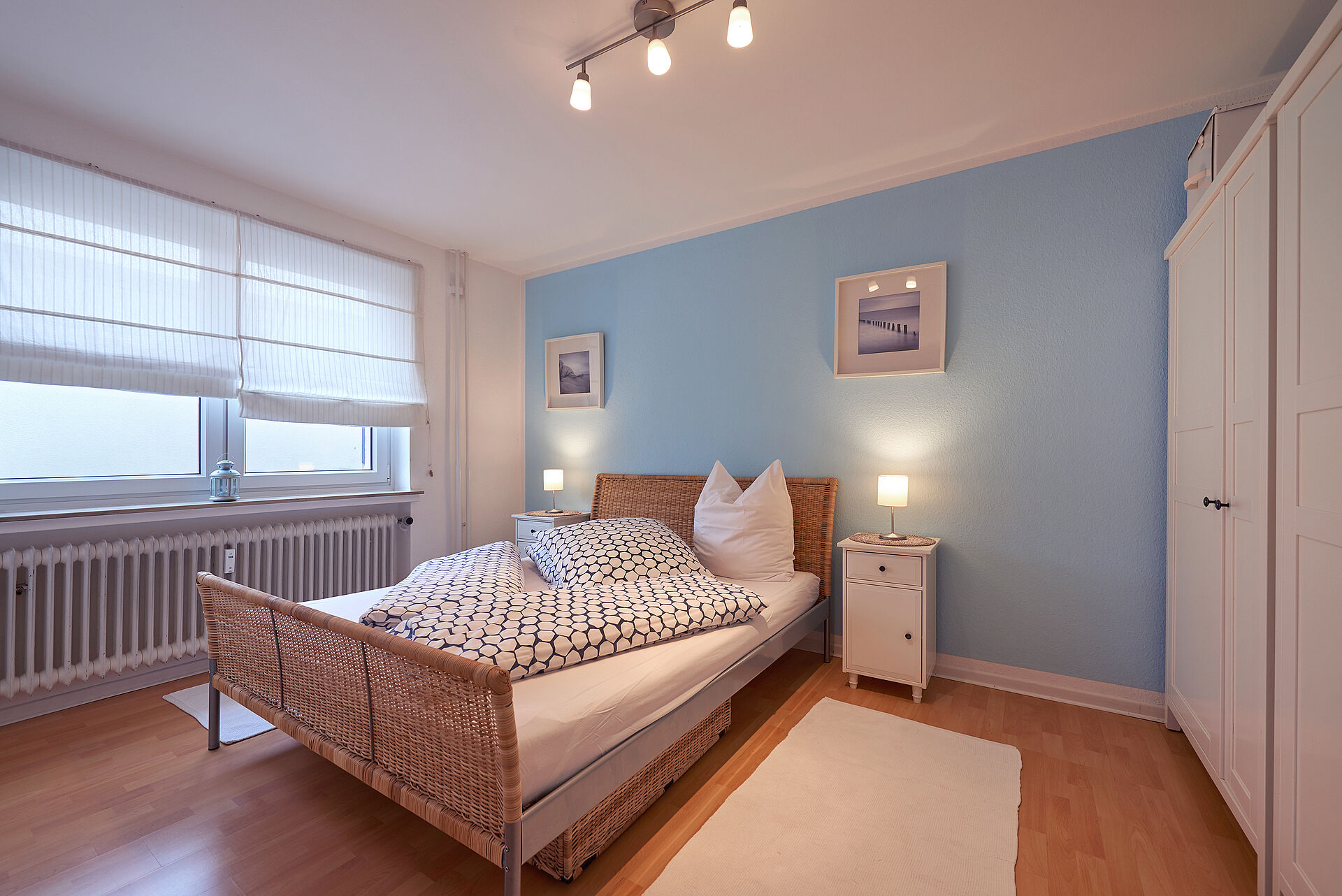Schlafzimmer mit einem Doppelbett vor einer hellblau gestrichenen Wand