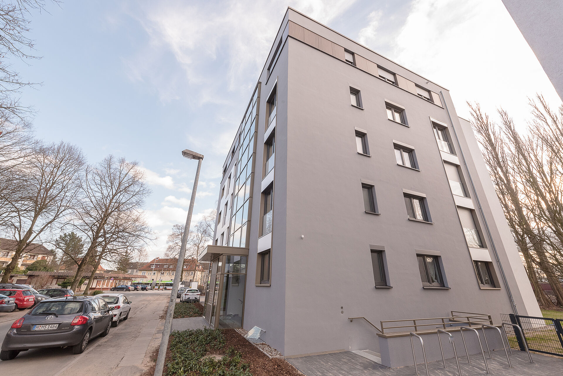 Mehrfamilienhaus mit steingrauer Fassade und großen Fenstern