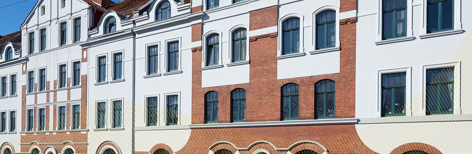 Elegantes Mehrfamilienhaus, teils mit rotbrauner Klinkerfassade und grünen Fensterrahmen