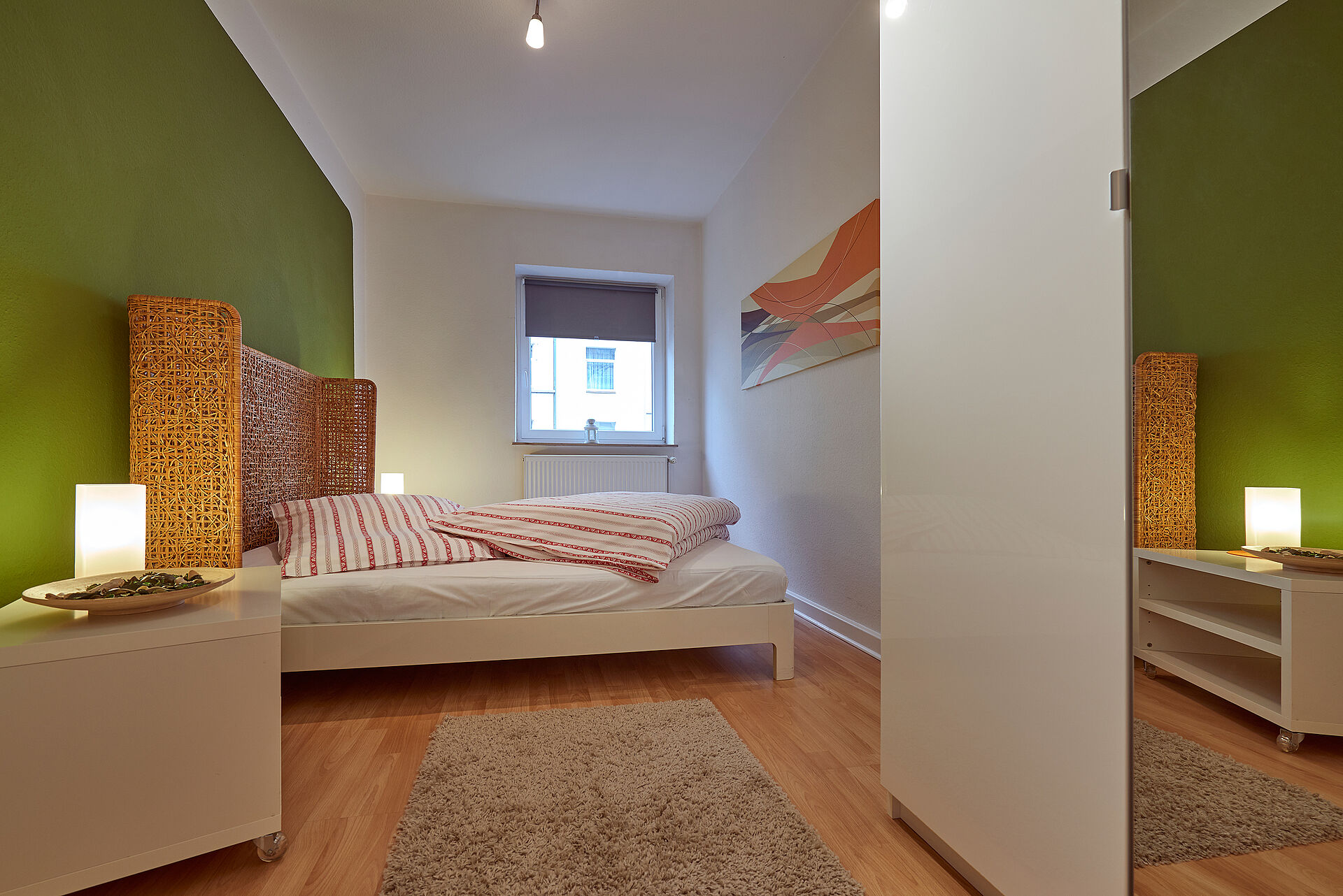 Schlafzimmer mit Doppelbett, einem Kleiderschrank und grün gestrichenen Wänden